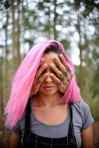 Cropped hands of man covering girlfriend eyes against trees