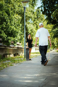 Couple with skateboards on footpath at park