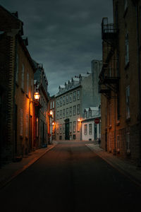 Empty road amidst buildings at night