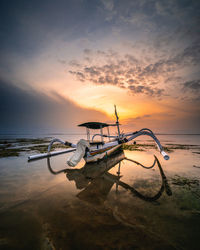 Fishing boats moored at shore against sky during sunset