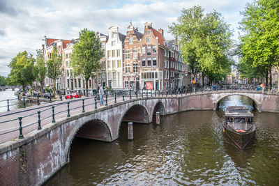 Bridge over river by buildings against sky