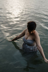 Rear view of woman sitting in sea