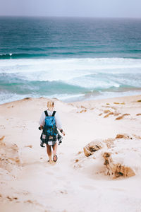 Rear view of woman walking at beach