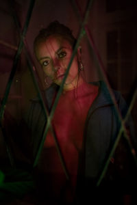 Portrait of young woman seen through fence