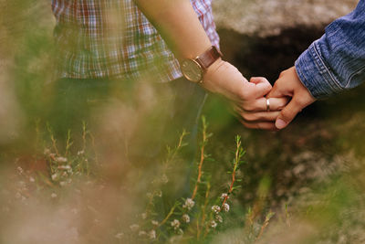 Cropped couple holding hands on field