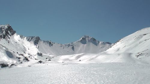 Scenic view of snowcapped mountains against clear blue sky