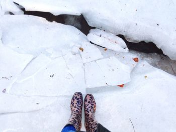 Low section of woman standing on ice formation