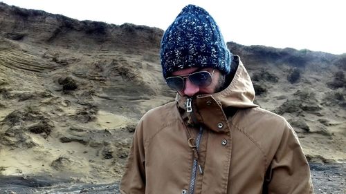 Portrait of man wearing sunglasses standing on sand