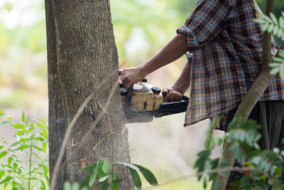 Midsection of man by tree trunk