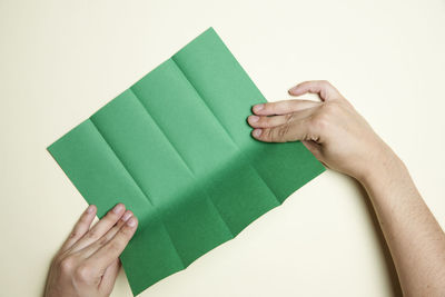 Midsection of person holding paper against white background