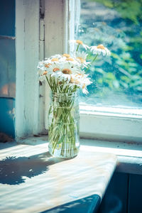 Close-up of flower vase on table by window