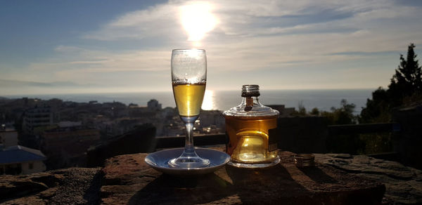 Wine glass on table against sky during sunset