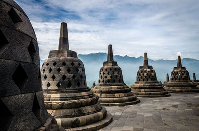 Stupas of temple against cloudy sky