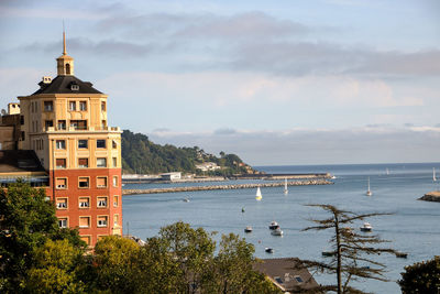 Buildings by sea against sky