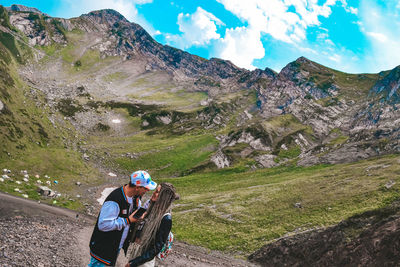 Rear view of woman climbing on mountain against sky