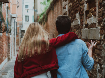 Rear view of couple kissing against buildings in city