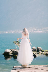 Rear view of woman standing by sea against sky