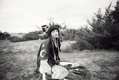 Portrait of young woman wearing cosplay costume sitting on field