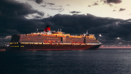 Illuminated commercial dock by sea against sky