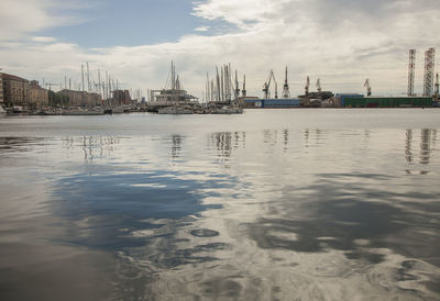 Cranes at harbor against sky