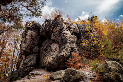 Rocks in forest against sky during autumn