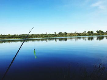 Fishing rod on lake against blue sky