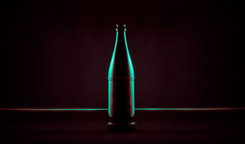 Close-up of illuminated green beer bottle against black background