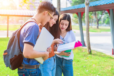 University students reading book at park