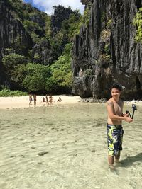 Man holding monopod while standing at beach