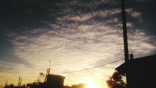 Low angle view of silhouette electricity pylon against sky during sunset