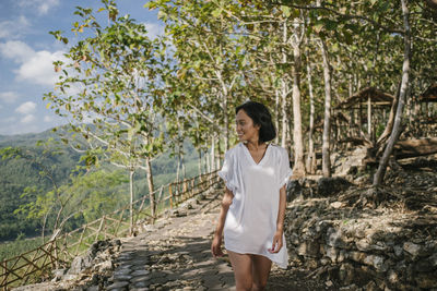 Portrait of young woman standing against plants