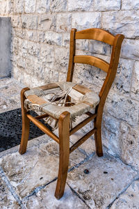 Empty chairs by stone wall