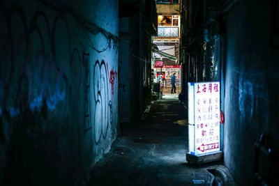 Graffiti on alley amidst buildings in city at night