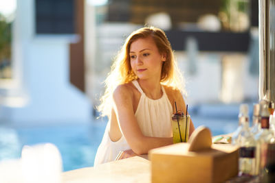 Young woman with drink sitting at sidewalk cafe