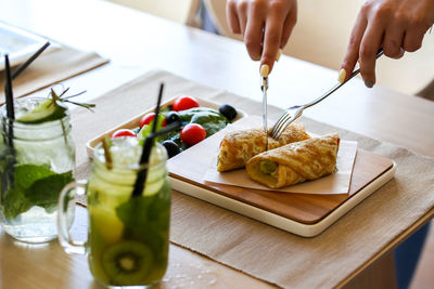 Cropped hands of woman having food and drinks at restaurant