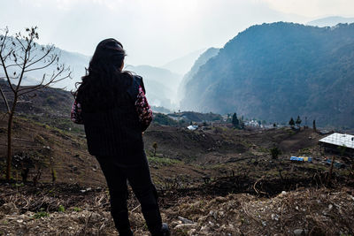 Young girl watching the misty mountain valley with sun rays beams at morning from flat angle