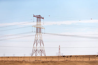 Low angle view of electricity pylon on field against sky