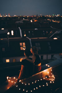 People sitting in illuminated town at night