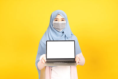 Low angle view of man using mobile phone against yellow background