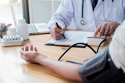 Midsection of man using mobile phone while sitting on table