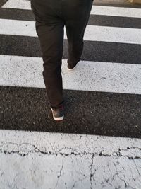 Low section of man walking on zebra crossing