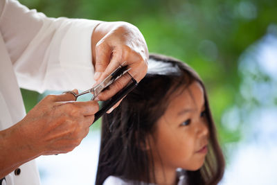 Midsection of grandmother cutting granddaughter hair