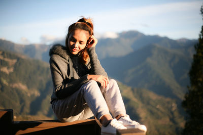 Mid adult woman sitting against mountains