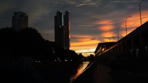 Silhouette buildings in city against sky during sunset