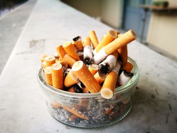 Close-up of cigarette butts in bowl on table