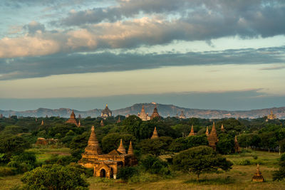 Old buddhist temples by mountains against sky during sunset