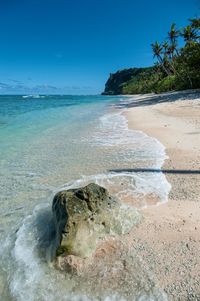 Scenic view of rocks on beach against blue sky