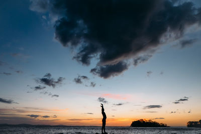 Silhouette man standing at beach against sky during sunset