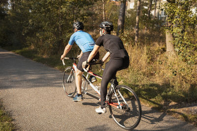 Visually impaired female triathlete training on tandem bicycle with her guide and coach