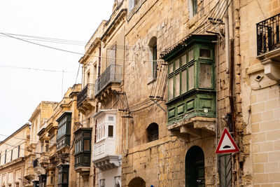 Typical maltese house with stone walls and window, wooden veranda